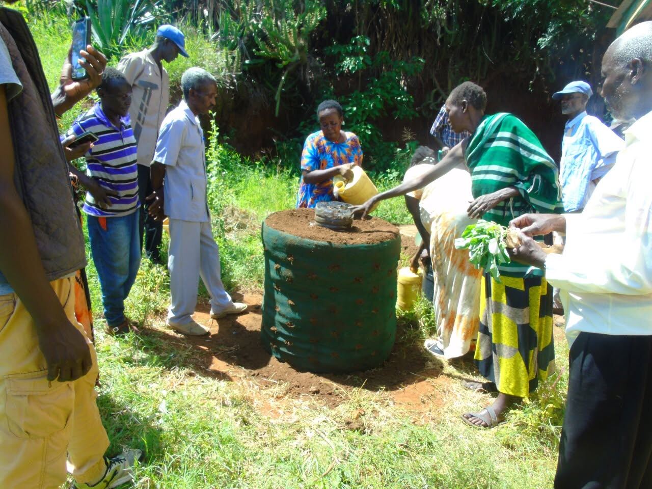 Community members planting seedlings into a sack garden